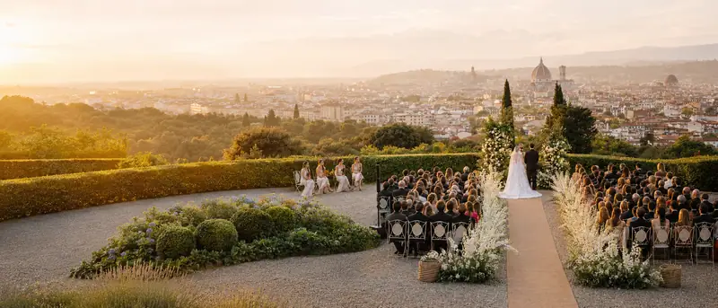 Gli sposi all'arco di fiori, la città sotto
