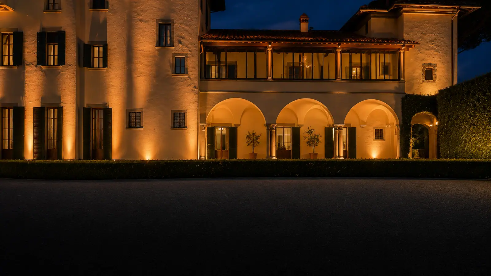 La facciata della villa illuminata di sera, con la lunga tavolata a lume di candela lungo la terrazza
